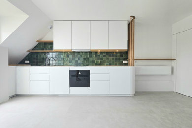 Aménagement d'une petite cuisine ouverte linéaire et blanche et bois bord de mer avec des portes de placard blanches, une crédence verte, une crédence en carreau briquette, un sol en vinyl, aucun îlot, un sol gris et un plan de travail blanc.