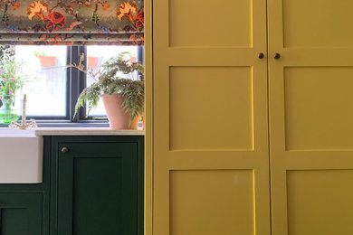 Photo of a small rural enclosed kitchen in Other with a belfast sink, shaker cabinets, brown floors and a feature wall.