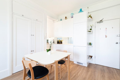 This is an example of a small contemporary galley eat-in kitchen in Wollongong with a double-bowl sink, flat-panel cabinets, white cabinets, quartz benchtops, mirror splashback, stainless steel appliances, vinyl floors, brown floor and white benchtop.