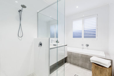 Design ideas for a contemporary bathroom in Perth with flat-panel cabinets, white cabinets, a drop-in tub, a corner shower, white tile, porcelain tile, white walls, porcelain floors, a drop-in sink, solid surface benchtops, grey floor, a hinged shower door and white benchtops.