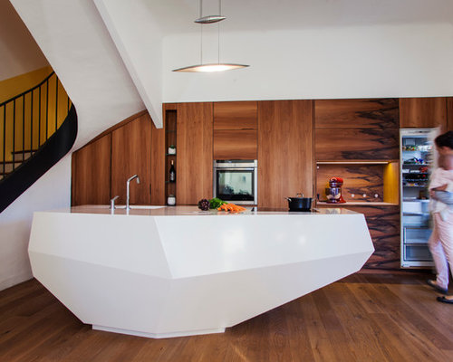 Idée de décoration pour une grande cuisine ouverte parallèle design avec un îlot central, un placard à porte plane, des portes de placard en bois brun, un électroménager en acier inoxydable, un sol en bois brun et un évier encastré.