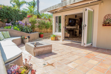 Inspiration for a large contemporary backyard patio in Orange County with a fire feature, tile and an awning.