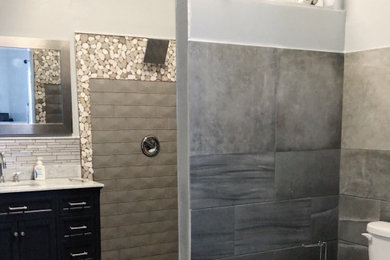 Example of a mid-sized minimalist master gray tile and porcelain tile cement tile floor and gray floor bathroom design in Tampa with black cabinets, a hot tub, a one-piece toilet, gray walls, an undermount sink, marble countertops and gray countertops