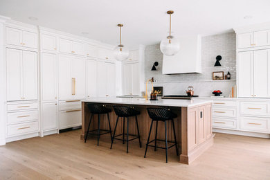 Inspiration for a mid-sized transitional eat-in kitchen remodel in Detroit with a drop-in sink, white cabinets, quartz countertops, white backsplash, ceramic backsplash, paneled appliances, an island and white countertops