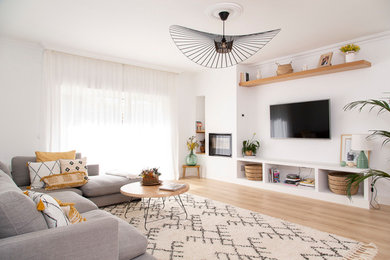 Imagen de salón abierto contemporáneo grande con paredes blancas, suelo de madera clara, todas las chimeneas, marco de chimenea de metal, televisor colgado en la pared y suelo beige