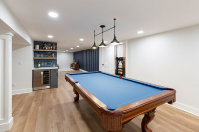 Example of a large transitional underground laminate floor basement game room design in New York with blue walls