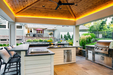 Inspiration for a mid-sized timeless backyard stone patio kitchen remodel in Minneapolis with a gazebo