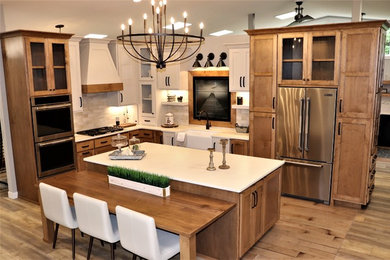Enclosed kitchen - mid-sized country l-shaped medium tone wood floor and brown floor enclosed kitchen idea in Other with an island, a farmhouse sink, shaker cabinets, medium tone wood cabinets, quartz countertops, beige backsplash, subway tile backsplash, stainless steel appliances and white countertops