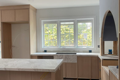 フィラデルフィアにある高級な広いコンテンポラリースタイルのおしゃれなキッチン (一体型シンク、シェーカースタイル扉のキャビネット、淡色木目調キャビネット、大理石カウンター、白いキッチンパネル、ガラスまたは窓のキッチンパネル、パネルと同色の調理設備、大理石の床、白い床、白いキッチンカウンター) の写真