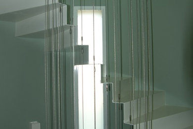 Diseño de escalera suspendida actual de tamaño medio con escalones de metal, contrahuellas de metal y barandilla de cable