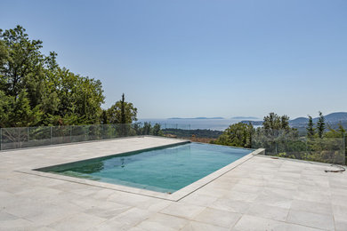 Aménagement d'une grande piscine à débordement et avant moderne rectangle avec du carrelage.