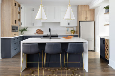 Example of a minimalist u-shaped medium tone wood floor and brown floor kitchen design in Toronto with shaker cabinets, light wood cabinets, quartz countertops, white backsplash, quartz backsplash, an island and white countertops