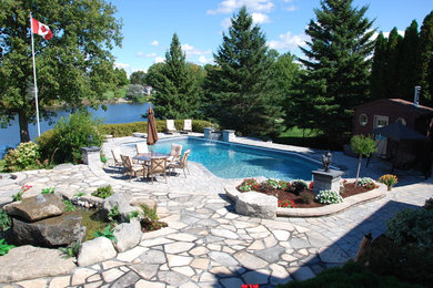 Example of a huge transitional backyard concrete paver and l-shaped pool design in Ottawa