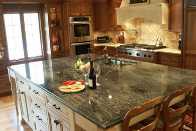 Eat-in kitchen - mediterranean eat-in kitchen idea in Boston with an undermount sink, recessed-panel cabinets, medium tone wood cabinets, quartz countertops, white backsplash, stone tile backsplash and stainless steel appliances