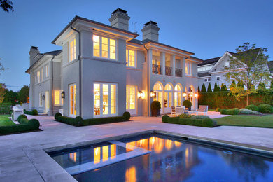 Inspiration for a large contemporary gray two-story stucco exterior home remodel in New York with a hip roof