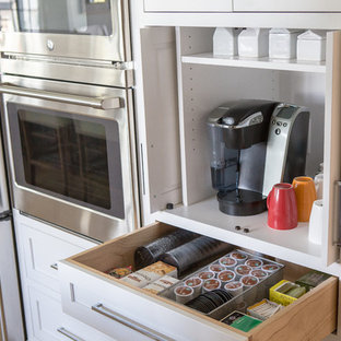 Inspiration pour une arrière-cuisine traditionnelle en U de taille moyenne avec un évier encastré, un placard à porte shaker, des portes de placard blanches, un plan de travail en marbre, une crédence grise, une crédence en marbre, un électroménager en acier inoxydable, un sol en bois clair, un îlot central et un sol marron.