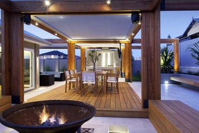 Mid-sized modern backyard deck in Sunshine Coast with a fire feature and a roof extension.