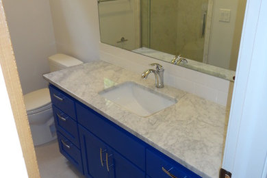Mid-sized transitional master white tile and stone slab porcelain tile and gray floor alcove shower photo in Oklahoma City with shaker cabinets, blue cabinets, a two-piece toilet, gray walls, an undermount sink, marble countertops and a hinged shower door
