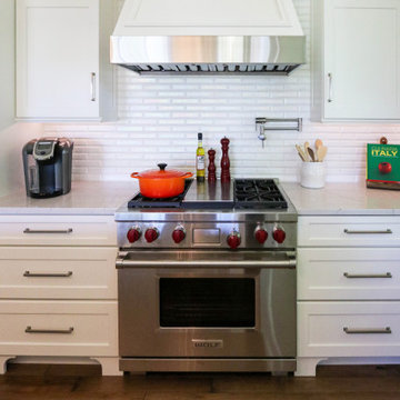 White Kitchen with Gray Quartz Countertops, Farmhouse Sink and Hardwood Floors