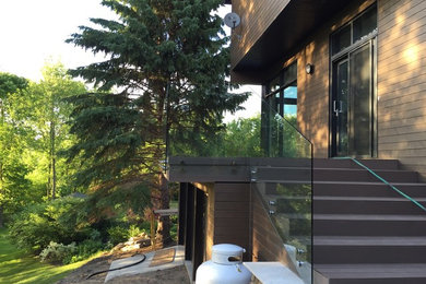 Example of a mid-sized minimalist backyard deck design in Montreal with no cover