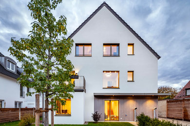Dreistöckiges Modernes Haus mit Putzfassade, weißer Fassadenfarbe, Satteldach, Ziegeldach und grauem Dach in München