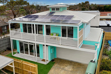 Photo of a mid-sized beach style two-storey blue house exterior in Melbourne with concrete fiberboard siding, a hip roof and a metal roof.