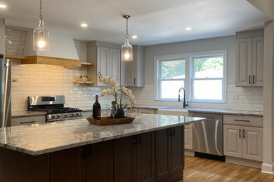 Inspiration for a transitional kitchen remodel in Atlanta with a farmhouse sink, shaker cabinets, gray cabinets, quartzite countertops, white backsplash, subway tile backsplash, stainless steel appliances, an island and gray countertops
