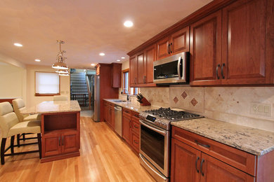 Inspiration for a mid-sized timeless light wood floor eat-in kitchen remodel in Boston with an undermount sink, raised-panel cabinets, medium tone wood cabinets, quartz countertops, beige backsplash, stone slab backsplash, stainless steel appliances and an island