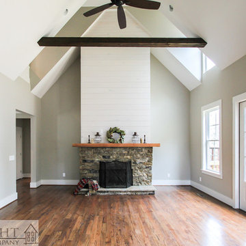Shiplap and rock fireplace with vaulted ceiling beams