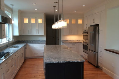Example of a large transitional u-shaped light wood floor, brown floor and vaulted ceiling kitchen pantry design in Boston with a single-bowl sink, shaker cabinets, white cabinets, quartz countertops, stainless steel appliances, an island and gray countertops