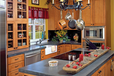 Inspiration for a timeless l-shaped eat-in kitchen remodel in Philadelphia with a farmhouse sink, beaded inset cabinets, medium tone wood cabinets, soapstone countertops, black backsplash, stone tile backsplash and stainless steel appliances