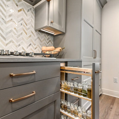 Example of a huge cottage l-shaped medium tone wood floor and brown floor eat-in kitchen design in Milwaukee with a farmhouse sink, shaker cabinets, gray cabinets, quartz countertops, white backsplash, marble backsplash, stainless steel appliances, an island and gray countertops