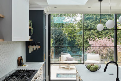 Large contemporary l-shaped open plan kitchen in London with shaker cabinets and an island.