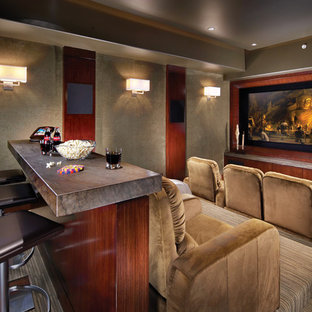 Example of an island style enclosed home theater design in Orange County with a media wall