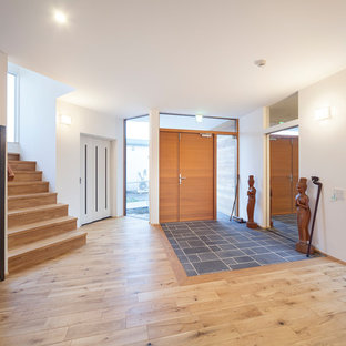 他の地域のアジアンスタイルのおしゃれな玄関 (白い壁、茶色いドア、茶色い床) の写真