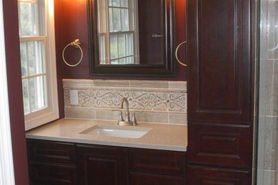 Example of a large trendy master multicolored tile and stone tile marble floor corner shower design in Other with raised-panel cabinets, dark wood cabinets, a two-piece toilet, red walls, an undermount sink and granite countertops