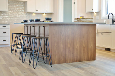 Inspiration for a large cottage l-shaped vinyl floor and brown floor eat-in kitchen remodel in Other with a farmhouse sink, shaker cabinets, medium tone wood cabinets, quartzite countertops, white backsplash, ceramic backsplash, an island and gray countertops