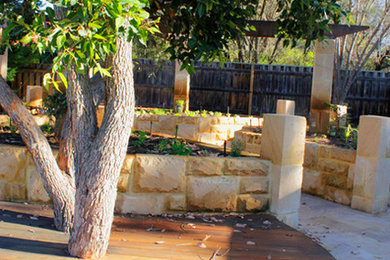 Inspiration for a large backyard partial sun garden for spring in Perth with a retaining wall and natural stone pavers.