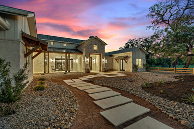 Large farmhouse white one-story stone exterior home idea in Austin with a metal roof