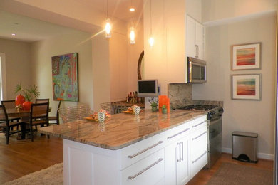 Kitchen - transitional galley medium tone wood floor kitchen idea in DC Metro with a drop-in sink, recessed-panel cabinets, white cabinets, granite countertops, stainless steel appliances and an island