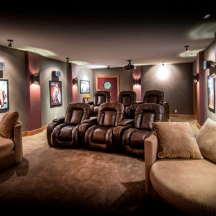 Large rustic enclosed home cinema in Omaha with brown walls, carpet, a projector screen and brown floors.