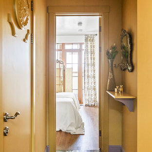 Idées déco pour une petite entrée éclectique avec un couloir, un mur jaune, un sol en marbre, un sol marron et une porte simple.