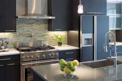 Eat-in kitchen - mid-sized contemporary l-shaped medium tone wood floor and brown floor eat-in kitchen idea in Denver with a farmhouse sink, flat-panel cabinets, black cabinets, granite countertops, green backsplash, glass tile backsplash, stainless steel appliances and an island