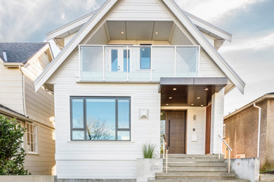 This is an example of a three-storey white house exterior in Vancouver with concrete fiberboard siding and a gable roof.