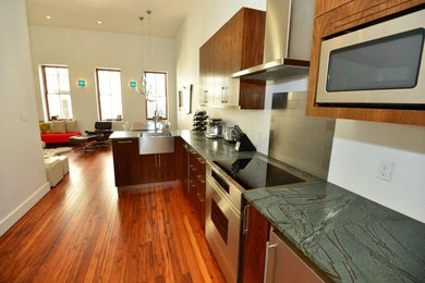 Open concept kitchen - small modern single-wall medium tone wood floor open concept kitchen idea in Atlanta with a farmhouse sink, flat-panel cabinets, medium tone wood cabinets, soapstone countertops, metallic backsplash, subway tile backsplash, stainless steel appliances and no island