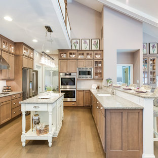 Mid-sized traditional u-shaped kitchen pantry in Other with a drop-in sink, recessed-panel cabinets, medium wood cabinets, quartz benchtops, white splashback, ceramic splashback, stainless steel appliances, medium hardwood floors, with island and brown floor.