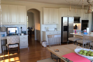 Eat-in kitchen - mid-sized transitional l-shaped medium tone wood floor eat-in kitchen idea in Denver with raised-panel cabinets, white cabinets, solid surface countertops, white backsplash, subway tile backsplash, stainless steel appliances and an island