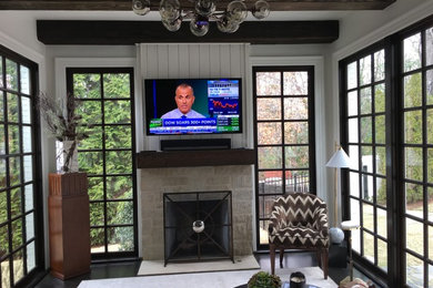 Inspiration for a mid-sized timeless enclosed dark wood floor and brown floor living room remodel in Atlanta with gray walls, a standard fireplace, a stone fireplace and a wall-mounted tv