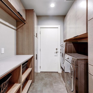 This is an example of a small modern galley separated utility room in Austin with flat-panel cabinets, light wood cabinets, engineered stone countertops, grey walls, ceramic flooring, a side by side washer and dryer and grey floors.