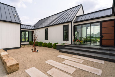 Example of a small minimalist white one-story concrete fiberboard and board and batten exterior home design in Columbus with a metal roof and a black roof